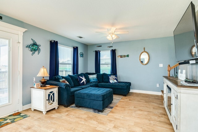 living area featuring ceiling fan, baseboards, visible vents, and light wood-type flooring