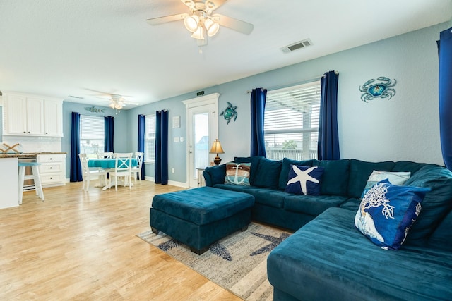 living area with light wood-style flooring, visible vents, and a ceiling fan