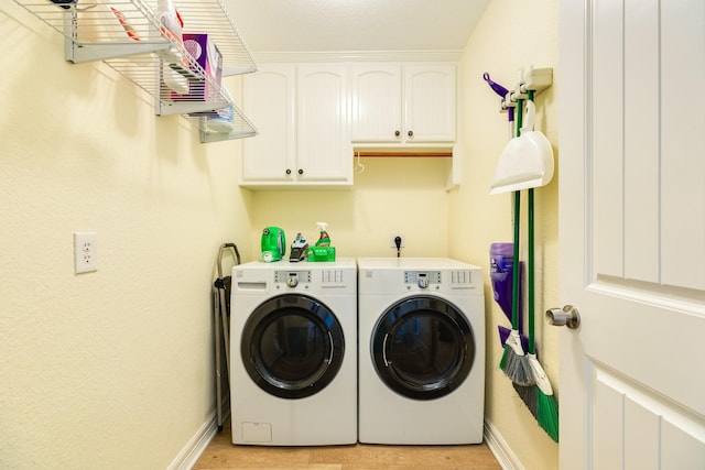 laundry room with light wood-style flooring, baseboards, washer and clothes dryer, and cabinet space