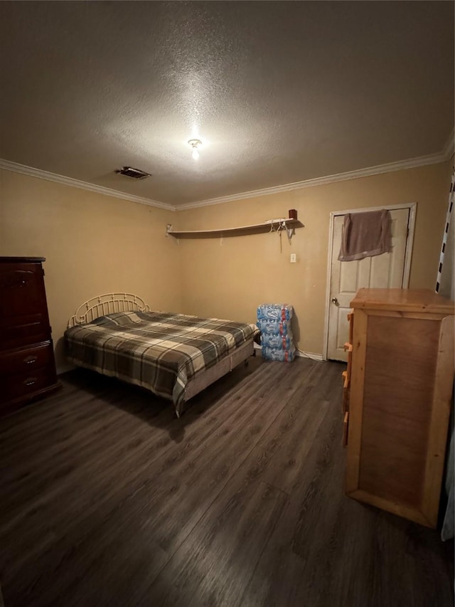 bedroom featuring ornamental molding, dark wood-style flooring, visible vents, and a textured ceiling