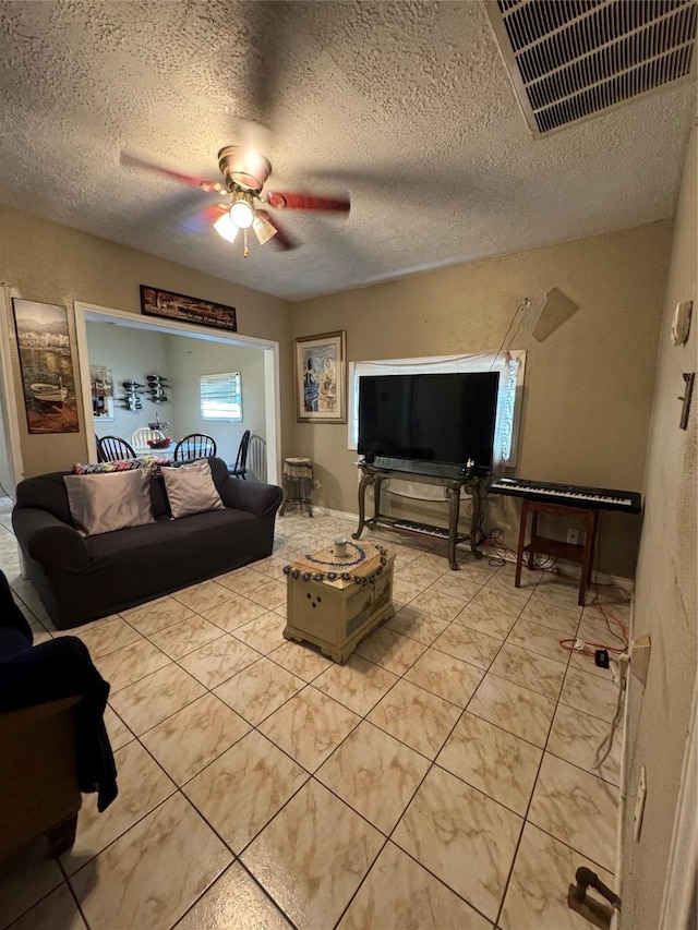 living area featuring ceiling fan, a textured ceiling, light tile patterned flooring, and visible vents