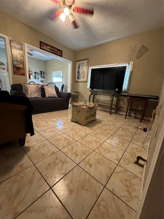 living room featuring a textured ceiling, light tile patterned floors, and a ceiling fan