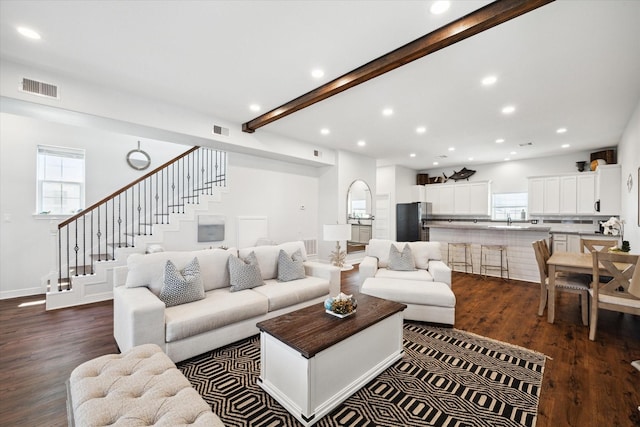 living room featuring beamed ceiling, dark wood-type flooring, and sink