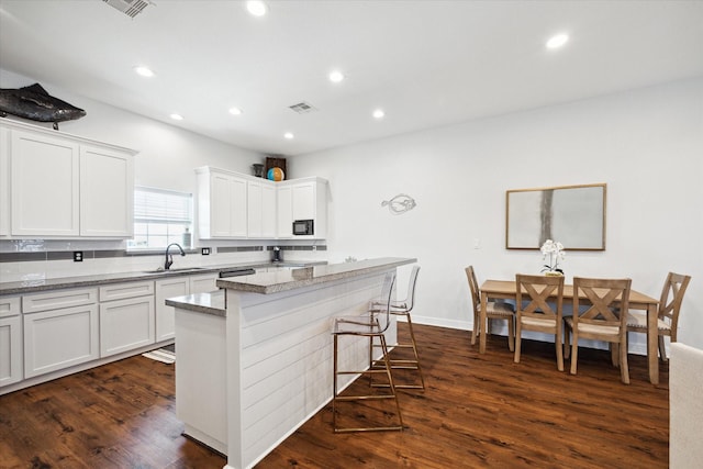 kitchen with white cabinets, dark hardwood / wood-style flooring, and light stone counters