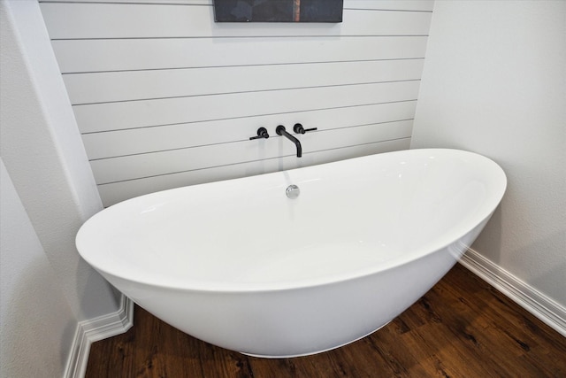 bathroom with a bath and hardwood / wood-style flooring