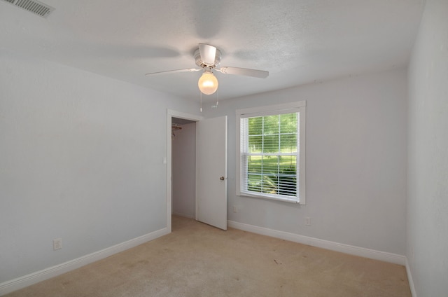 carpeted empty room with ceiling fan and a textured ceiling