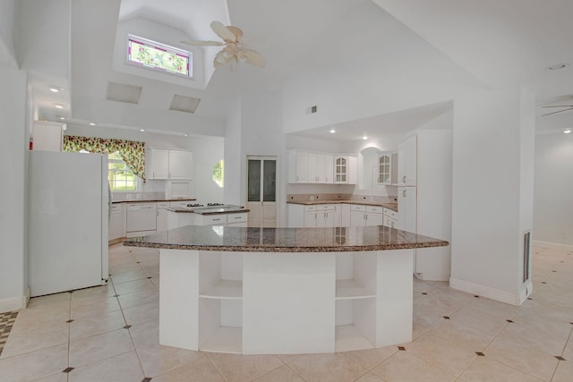 kitchen featuring a towering ceiling, white appliances, a kitchen island, light tile patterned floors, and white cabinetry