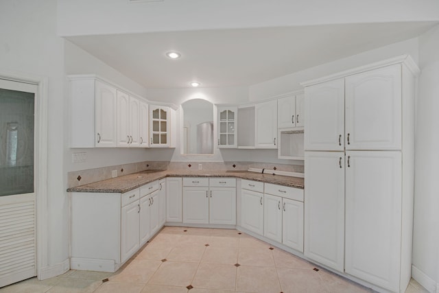 kitchen with white cabinets, light tile patterned flooring, and stone countertops