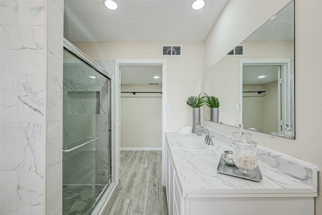 bathroom with hardwood / wood-style floors, an enclosed shower, and vanity with extensive cabinet space