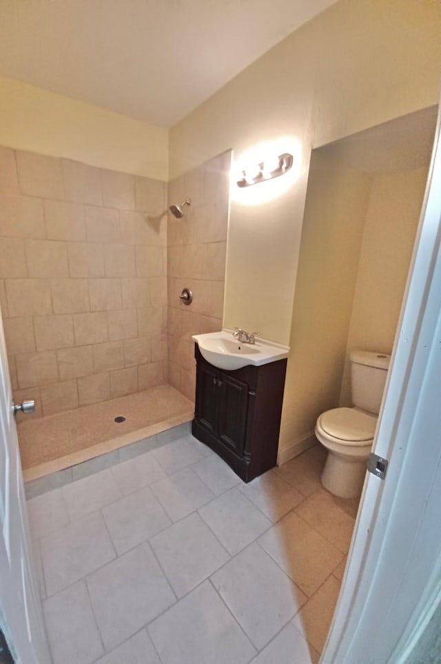 bathroom featuring vanity, a tile shower, tile patterned floors, and toilet