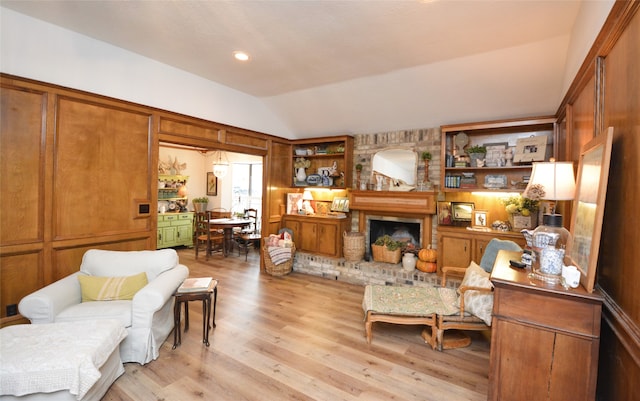 living room featuring vaulted ceiling, light hardwood / wood-style flooring, and a fireplace