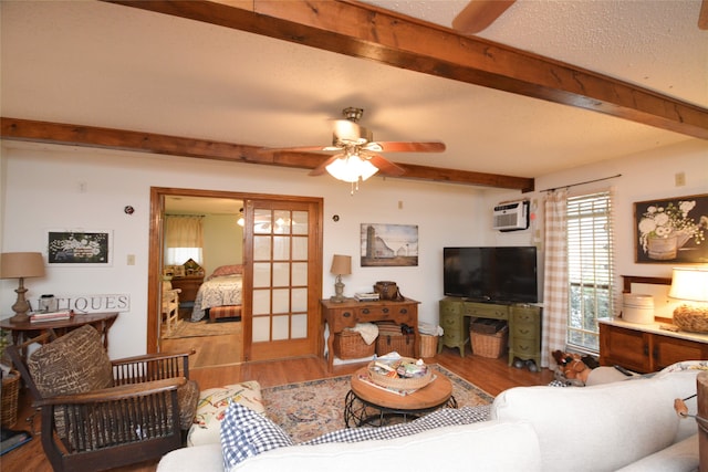 living room with hardwood / wood-style floors, beamed ceiling, a textured ceiling, a wall mounted air conditioner, and ceiling fan