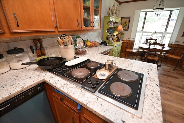 kitchen with decorative backsplash, wood-type flooring, dishwashing machine, light stone counters, and decorative light fixtures