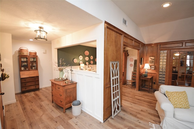 hall featuring vaulted ceiling and light hardwood / wood-style flooring