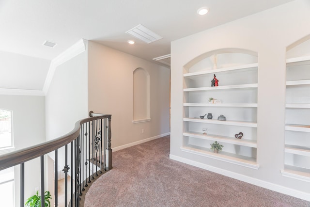 hallway with built in shelves, carpet floors, and ornamental molding