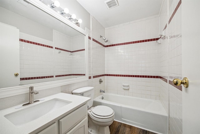 full bathroom with hardwood / wood-style floors, tiled shower / bath combo, toilet, and vanity