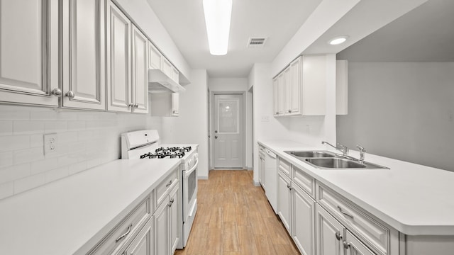 kitchen with sink, tasteful backsplash, light hardwood / wood-style flooring, white appliances, and white cabinets