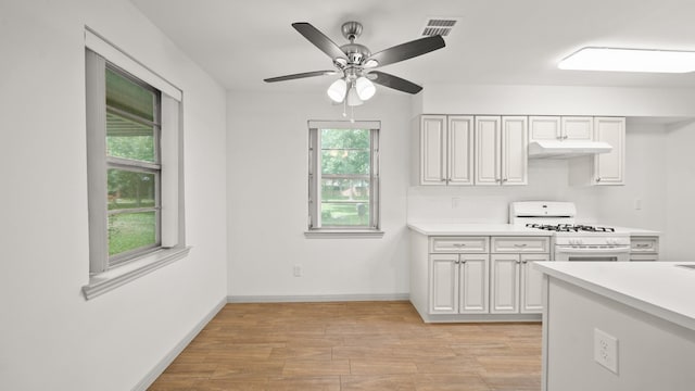 kitchen with white range with gas cooktop, ceiling fan, white cabinets, and light hardwood / wood-style floors