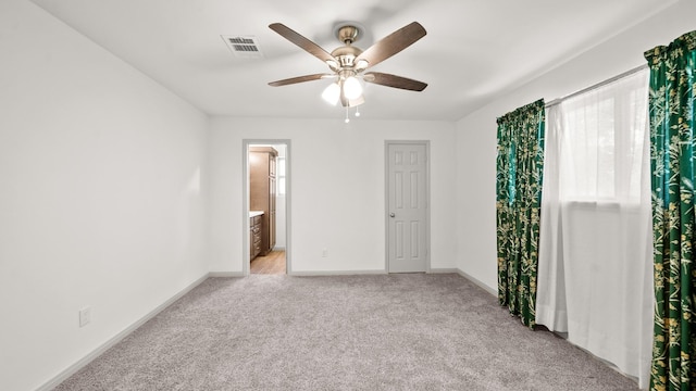 unfurnished bedroom featuring ceiling fan, light carpet, and ensuite bath