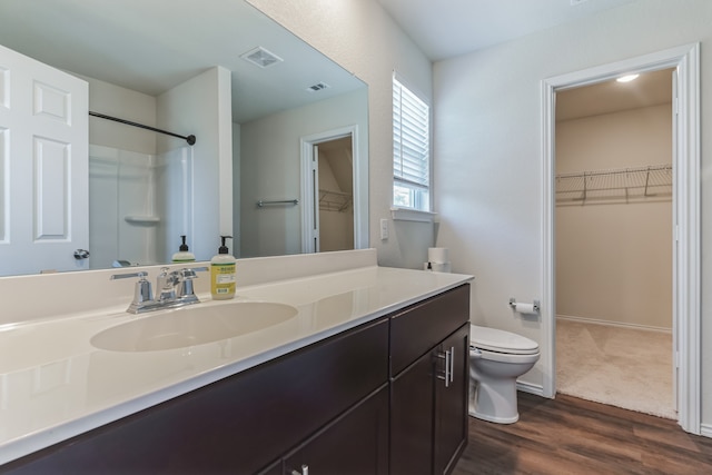 bathroom featuring vanity, hardwood / wood-style floors, toilet, and walk in shower