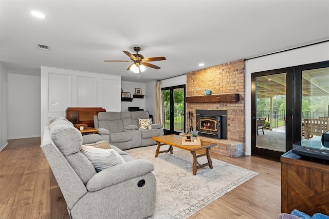 living room with ceiling fan, light hardwood / wood-style floors, and a wood stove