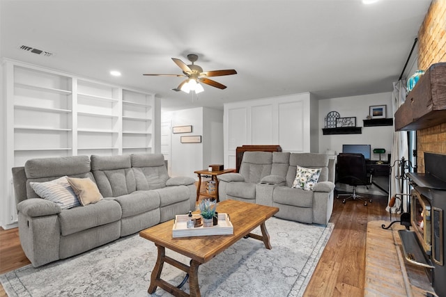 living room with wood-type flooring, ceiling fan, and built in shelves