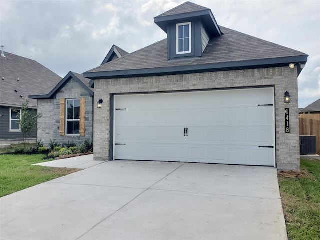 view of front of house with an attached garage, central AC, brick siding, driveway, and stone siding