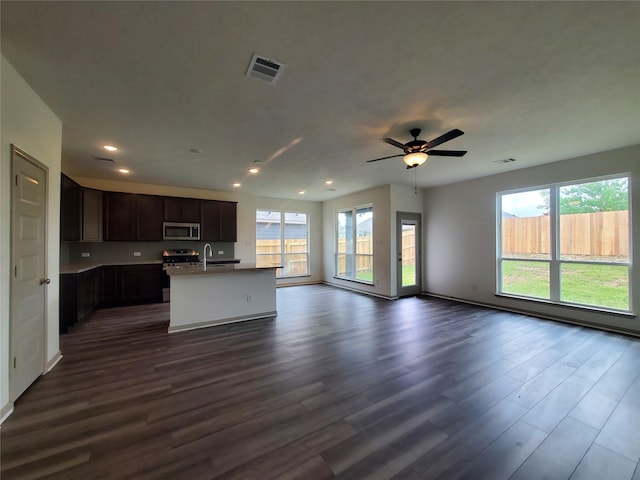 kitchen featuring stainless steel appliances, a sink, visible vents, open floor plan, and an island with sink