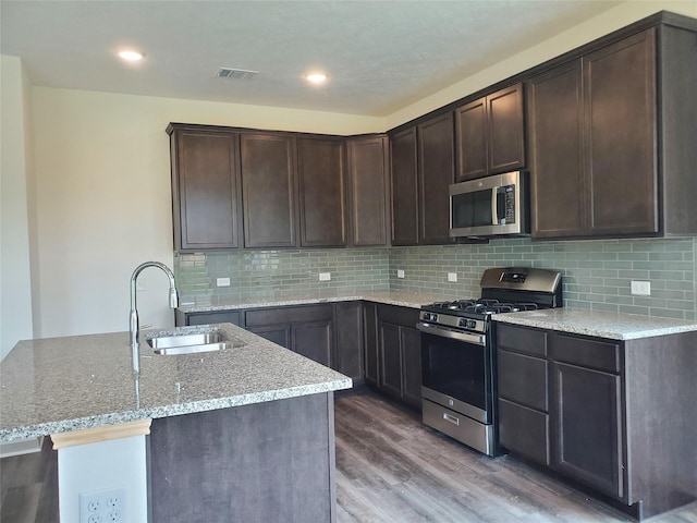 kitchen with stainless steel appliances, visible vents, a sink, dark brown cabinets, and wood finished floors