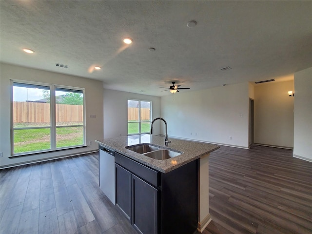 kitchen with a center island with sink, visible vents, a sink, light stone countertops, and stainless steel dishwasher