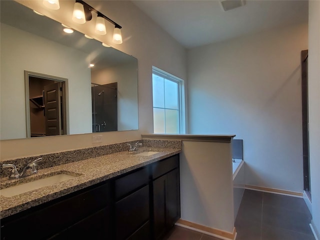 full bath featuring a stall shower, a sink, a spacious closet, and tile patterned floors