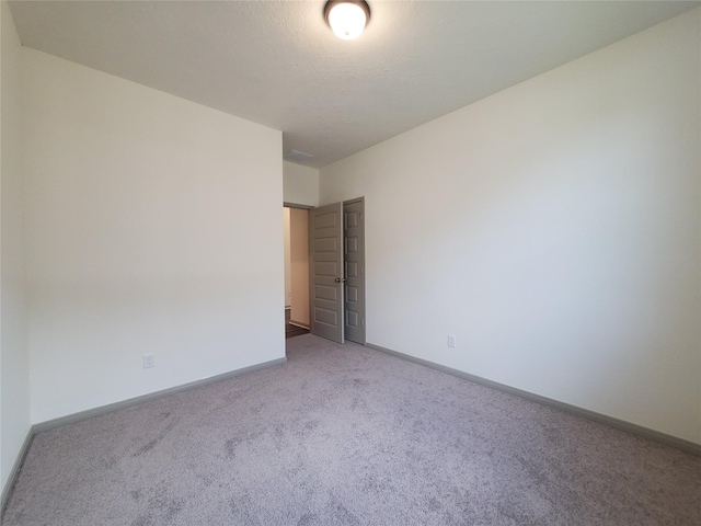 unfurnished room with light carpet and baseboards