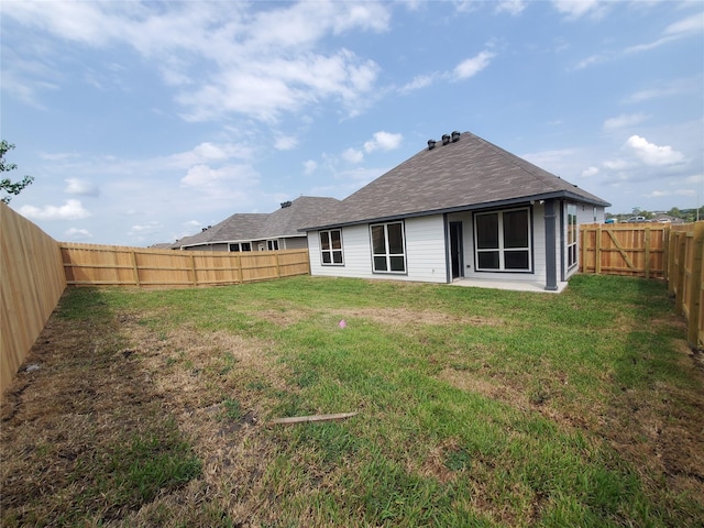 rear view of property with a fenced backyard, a lawn, and a patio