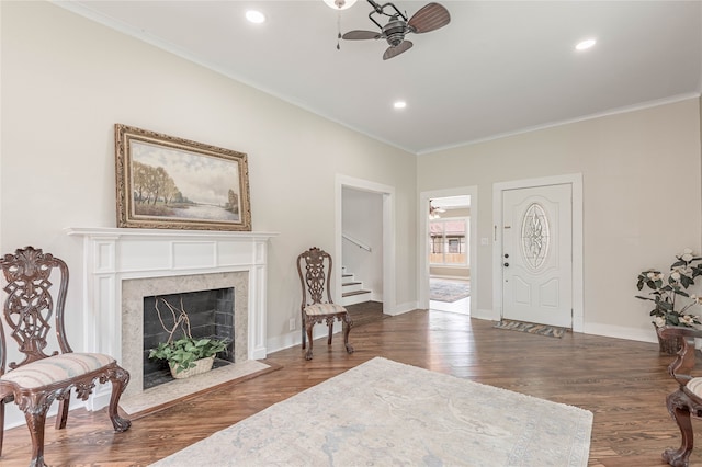 interior space with a premium fireplace, ornamental molding, dark wood-type flooring, and ceiling fan