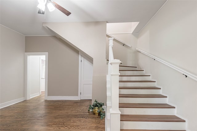 staircase featuring dark wood-type flooring, ceiling fan, and crown molding