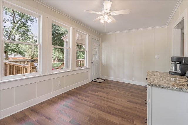 unfurnished dining area featuring ornamental molding, plenty of natural light, and dark hardwood / wood-style flooring