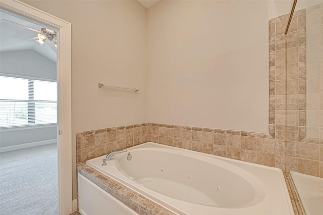 bathroom with a relaxing tiled tub, ceiling fan, and vaulted ceiling