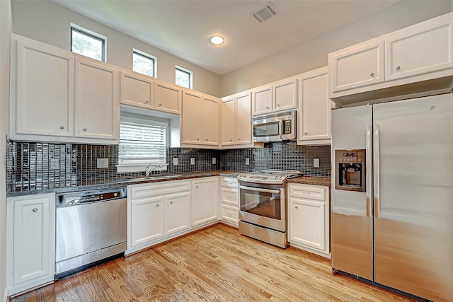 kitchen featuring white cabinets, sink, light wood-type flooring, appliances with stainless steel finishes, and a healthy amount of sunlight