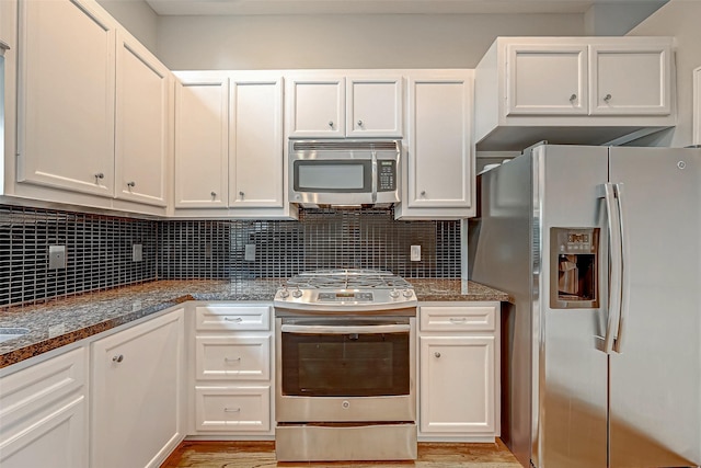 kitchen featuring backsplash, dark stone countertops, white cabinetry, and appliances with stainless steel finishes