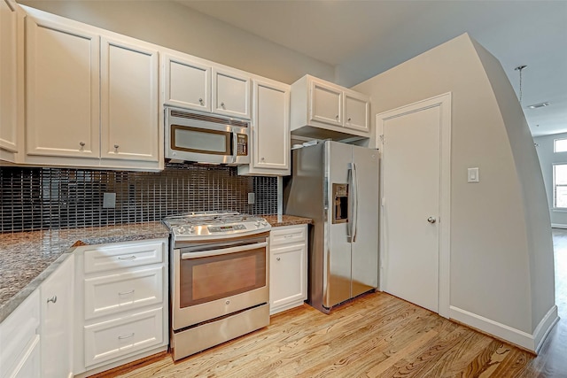 kitchen featuring stone counters, white cabinets, light hardwood / wood-style flooring, tasteful backsplash, and stainless steel appliances