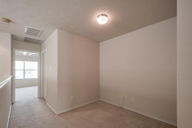 unfurnished room featuring light carpet and a textured ceiling