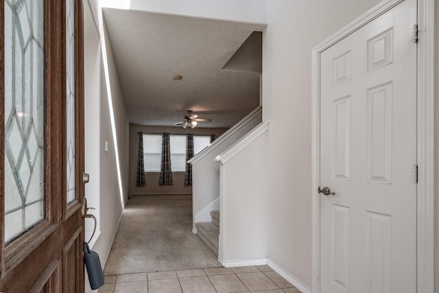 tiled foyer entrance with ceiling fan and a textured ceiling