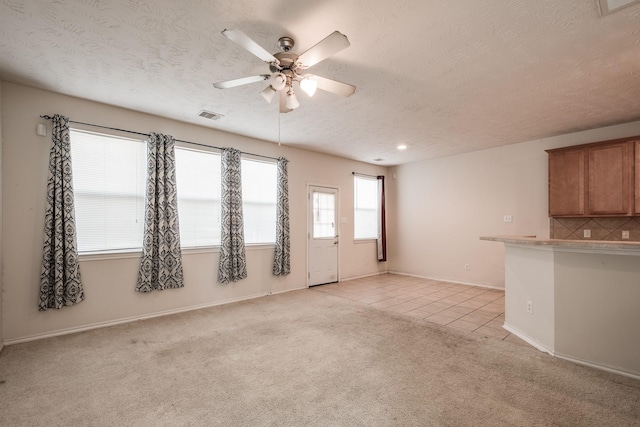 unfurnished living room with light carpet, a textured ceiling, and ceiling fan