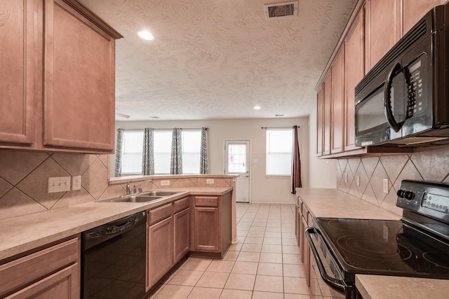 kitchen with kitchen peninsula, a textured ceiling, sink, black appliances, and light tile patterned floors