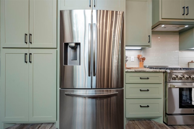 kitchen with green cabinetry, appliances with stainless steel finishes, backsplash, light stone countertops, and custom range hood