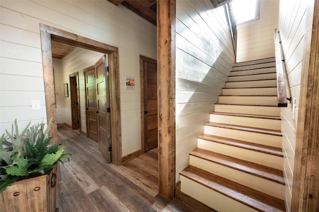 stairs featuring wood-type flooring and wood walls