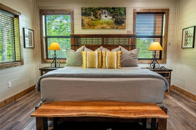 bedroom featuring wood walls, baseboards, and wood finished floors