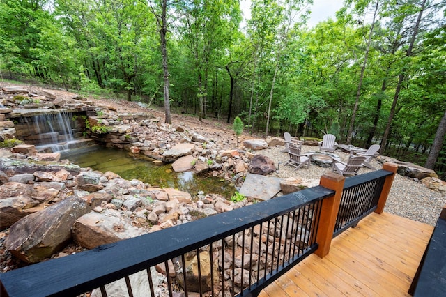 deck with an outdoor fire pit and a view of trees