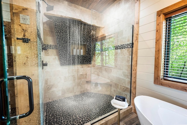 bathroom with a shower stall, wooden walls, and a freestanding bath