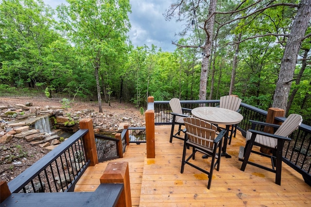 wooden deck featuring outdoor dining area and a wooded view